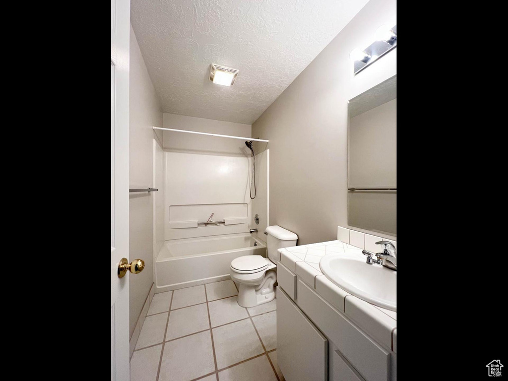 Full bathroom featuring washtub / shower combination, toilet, a textured ceiling, vanity, and tile patterned floors