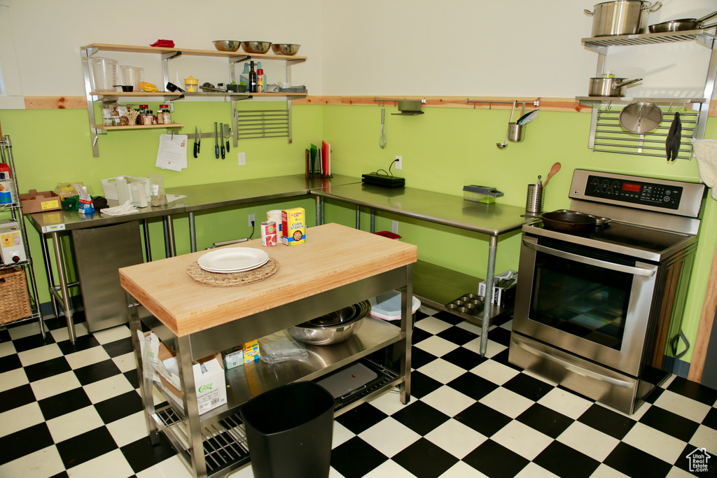 Kitchen featuring tile patterned floors, stainless steel electric range oven, and open shelves