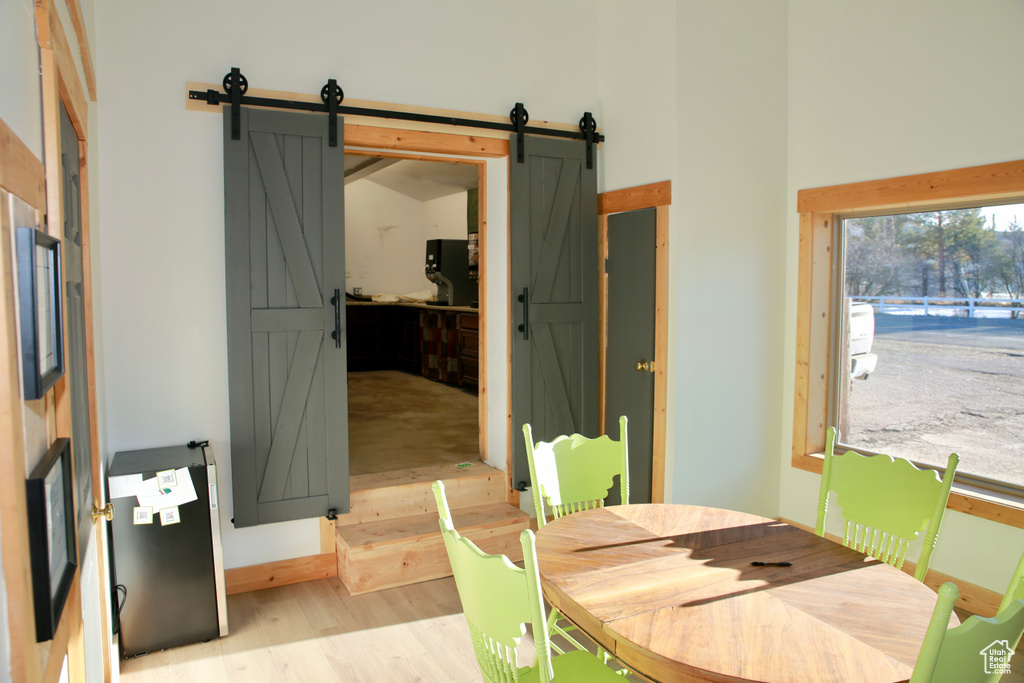 Dining room featuring a barn door, a high ceiling, and wood finished floors