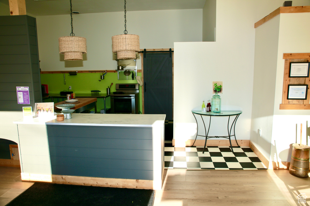 Kitchen with a barn door, range, a peninsula, and hanging light fixtures