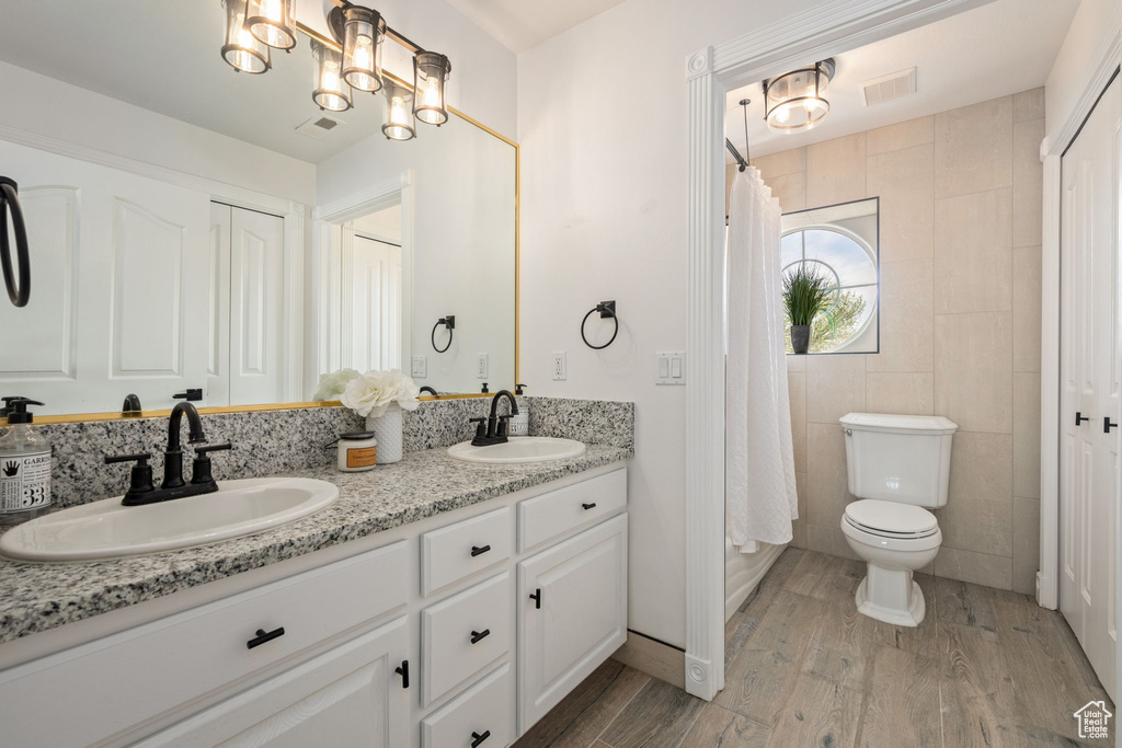 Bathroom featuring visible vents, a sink, double vanity, and wood finished floors