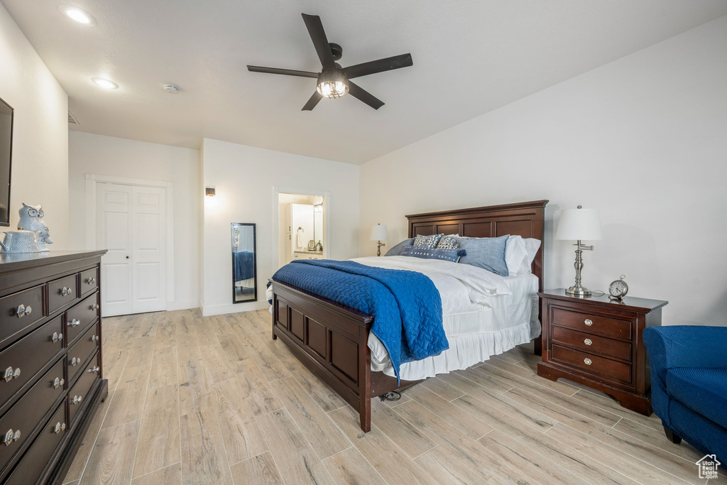Bedroom with light wood-style floors, ensuite bath, and a ceiling fan