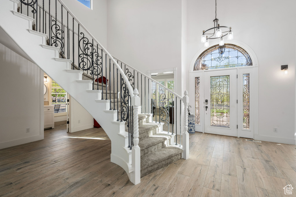 Foyer featuring baseboards, a chandelier, stairway, and hardwood / wood-style floors