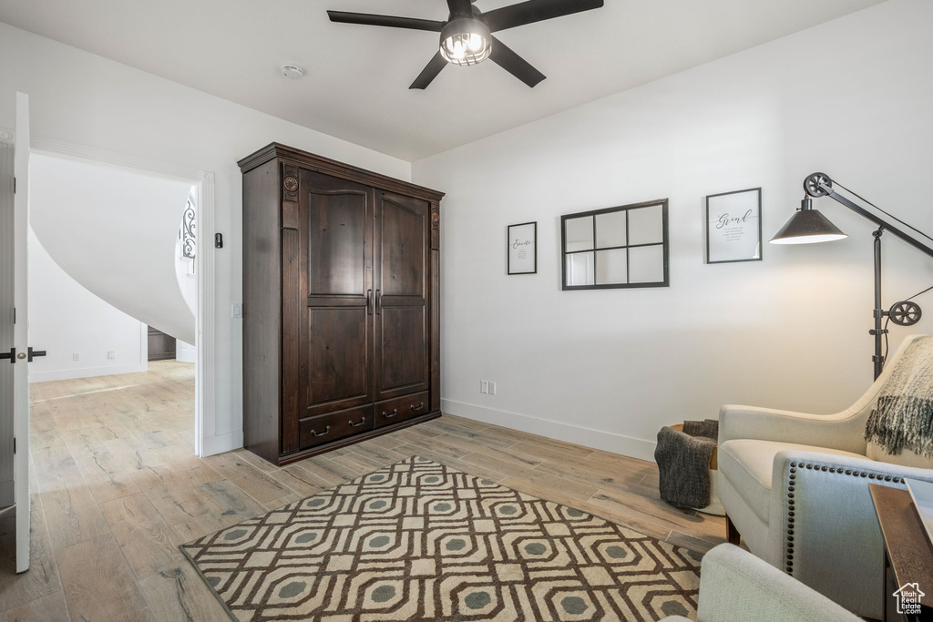 Sitting room with baseboards, light wood-style floors, and ceiling fan