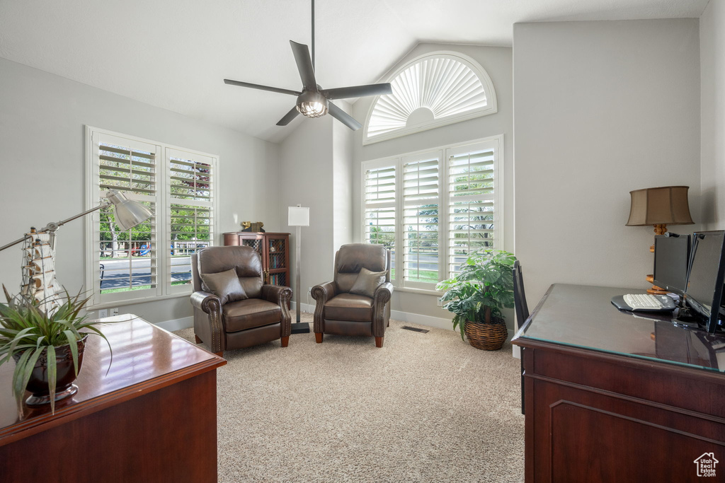 Carpeted office space with visible vents, baseboards, vaulted ceiling, and ceiling fan