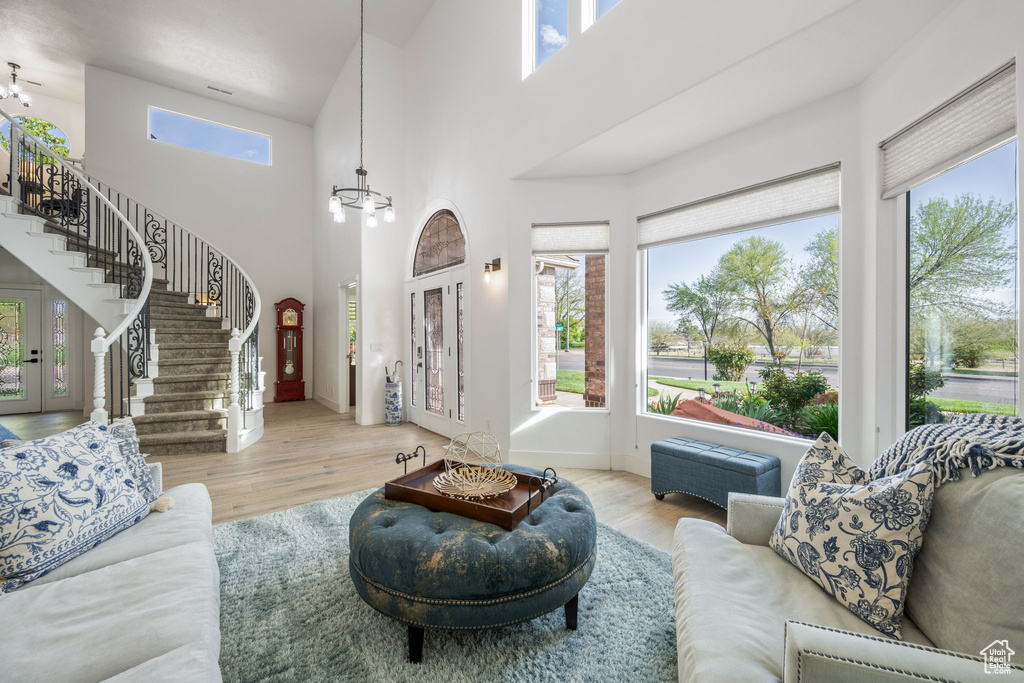 Living room featuring stairs, a high ceiling, wood finished floors, and an inviting chandelier