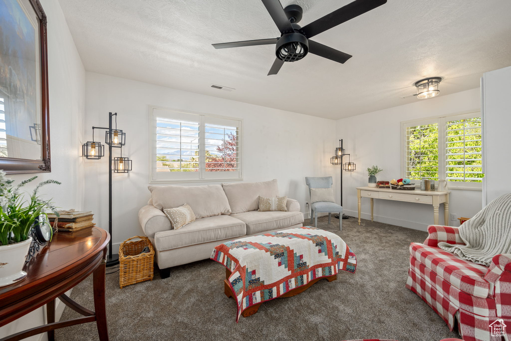 Living area with carpet floors, visible vents, a healthy amount of sunlight, and a ceiling fan