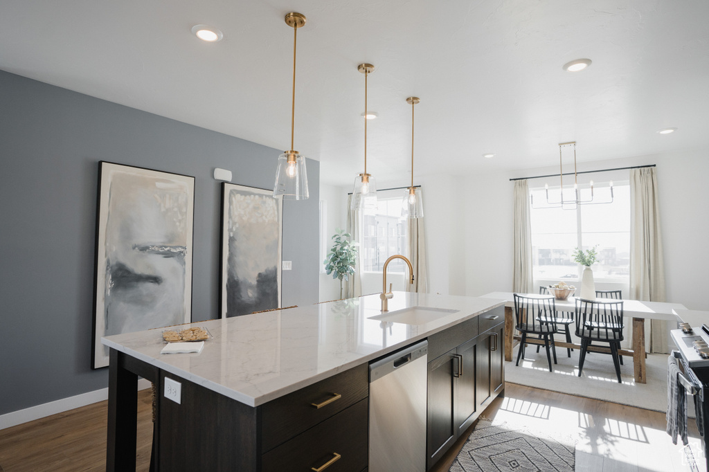 Kitchen featuring baseboards, light stone countertops, stainless steel appliances, a sink, and wood finished floors