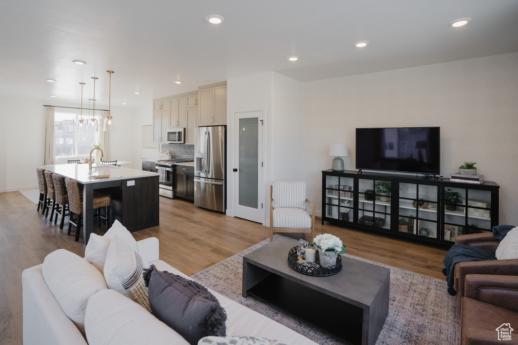 Living area with a chandelier, recessed lighting, baseboards, and light wood-style flooring