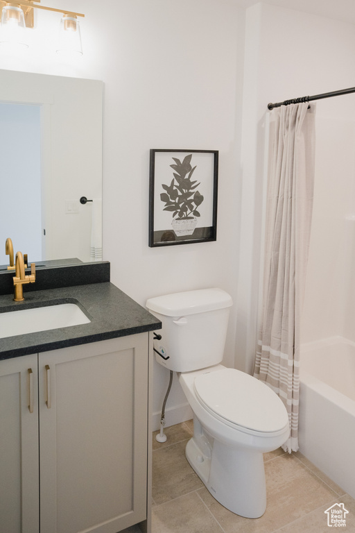Full bath featuring toilet, tile patterned floors, shower / bathtub combination with curtain, and vanity