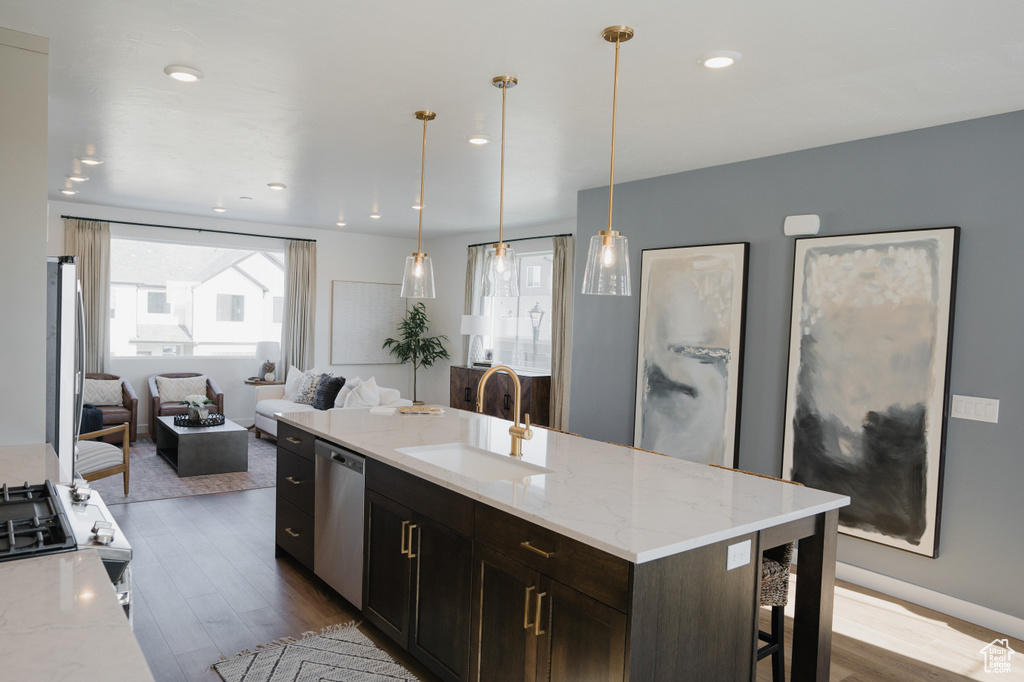 Kitchen featuring stainless steel dishwasher, open floor plan, a sink, and a healthy amount of sunlight
