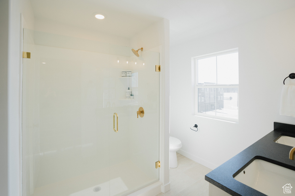 Bathroom with a sink, toilet, a shower stall, and double vanity