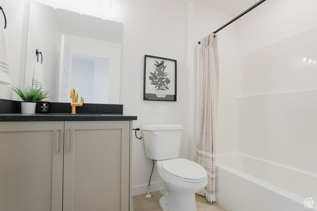 Full bathroom with vanity, toilet, tile patterned floors, shower / bath combo with shower curtain, and baseboards