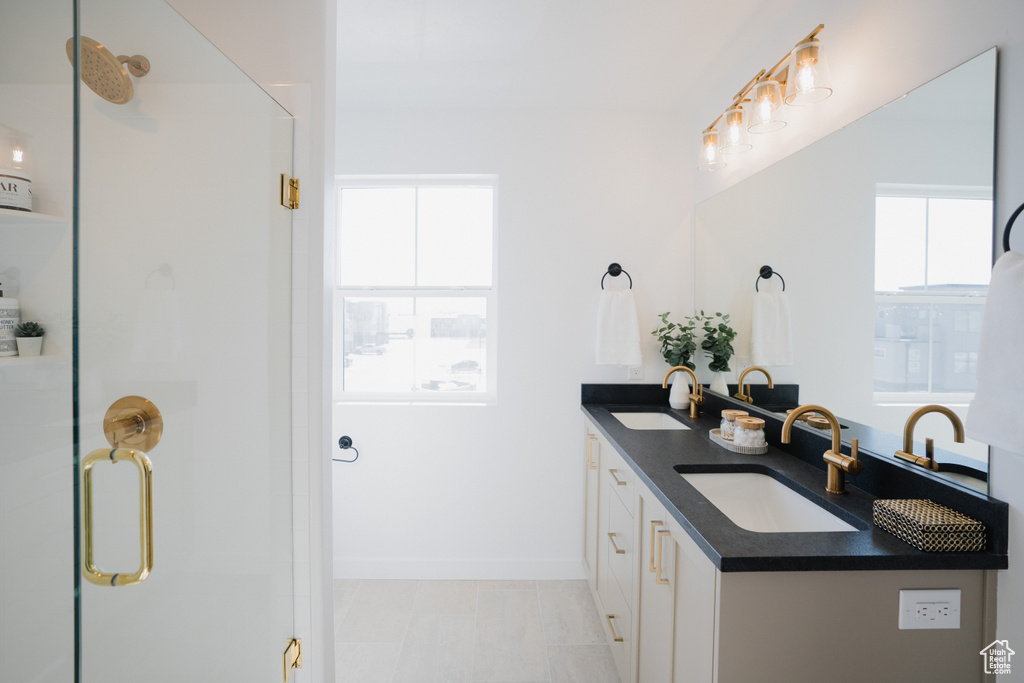 Full bathroom with a sink, baseboards, a shower stall, and double vanity
