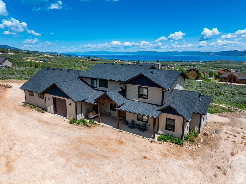 View of front of house with roof with shingles, a garage, a mountain view, dirt driveway, and board and batten siding