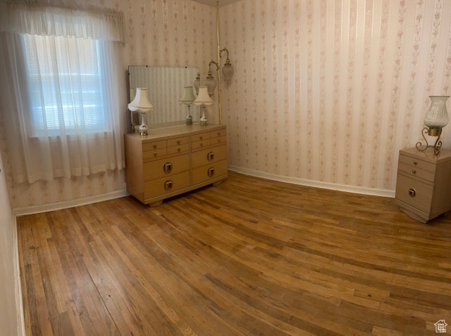 Bedroom featuring wallpapered walls and hardwood / wood-style floors