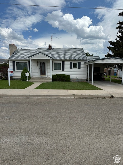 Single story home with a chimney, a front yard, and a carport