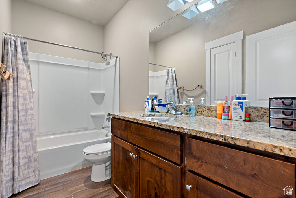 Full bath featuring shower / bath combination with curtain, vanity, toilet, and wood finished floors