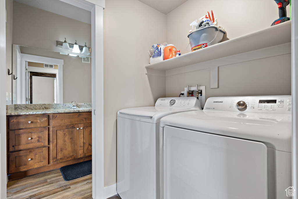 Washroom featuring visible vents, independent washer and dryer, laundry area, and wood finished floors