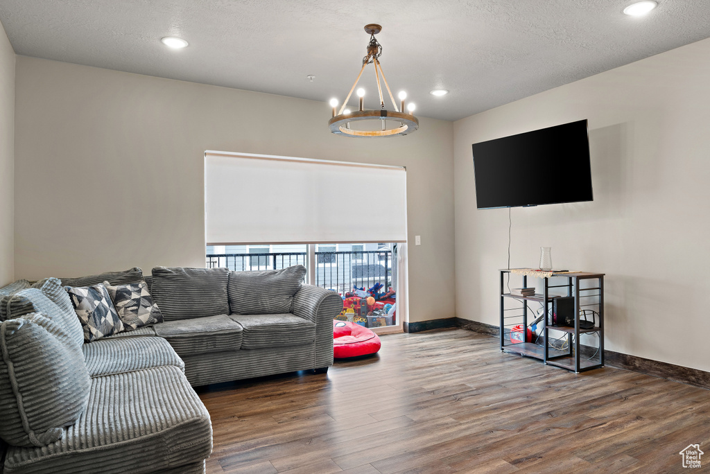 Living room featuring baseboards, a notable chandelier, a textured ceiling, recessed lighting, and wood finished floors