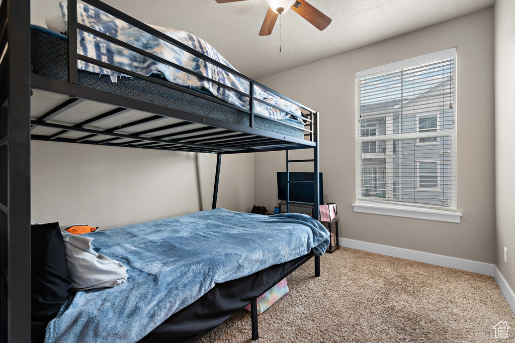 Carpeted bedroom featuring ceiling fan and baseboards