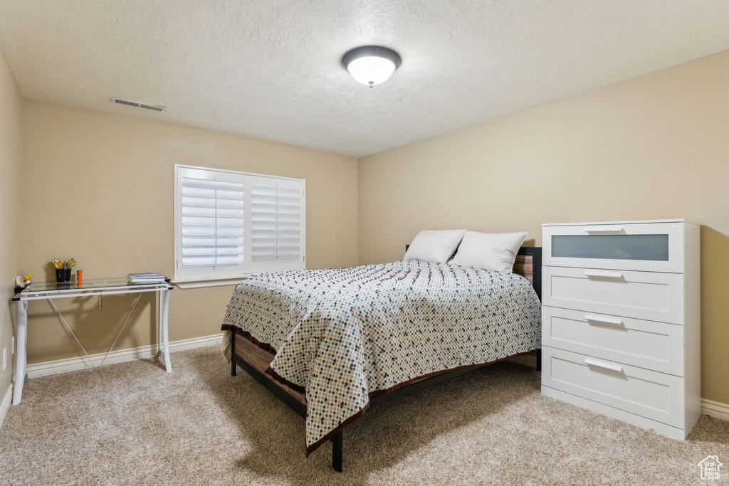 Carpeted bedroom with visible vents, a textured ceiling, and baseboards