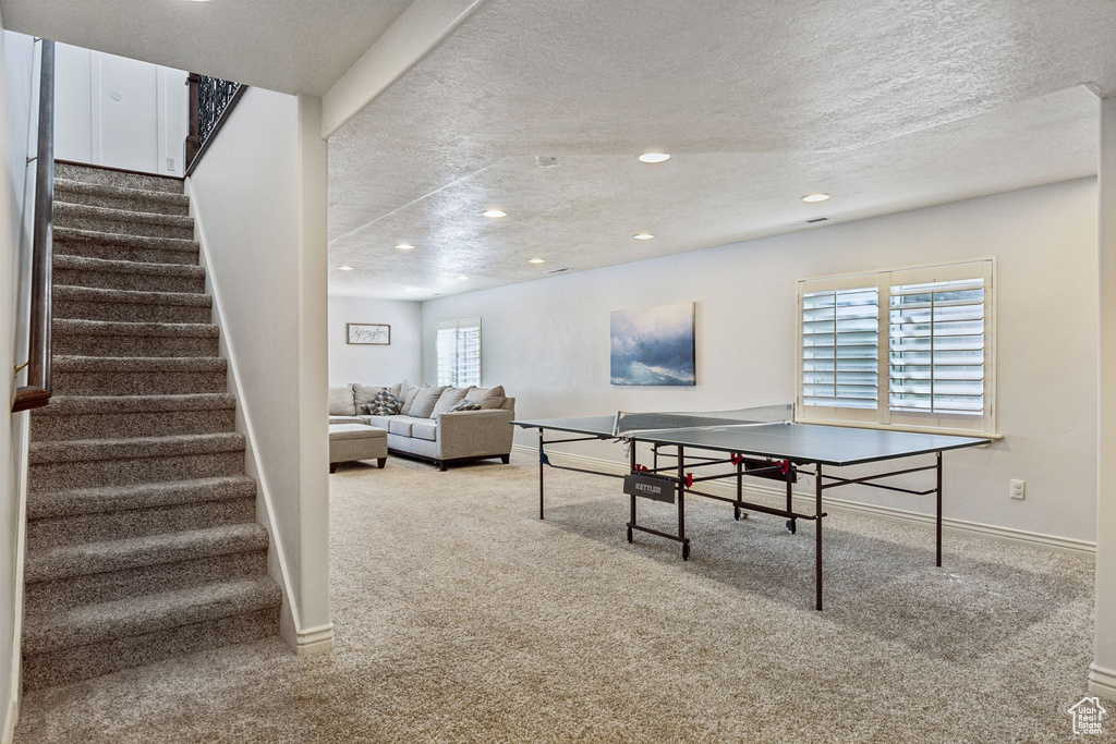 Recreation room featuring a textured ceiling, baseboards, carpet, and recessed lighting