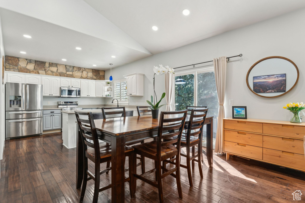 Dining area featuring dark wood-style floors, vaulted ceiling, and recessed lighting