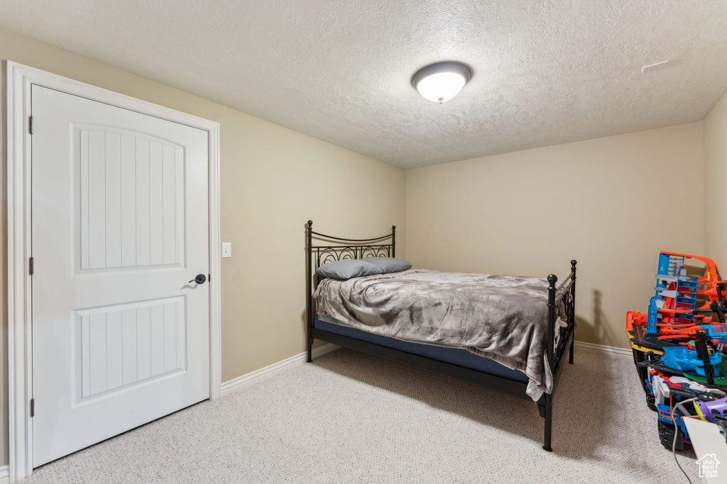 Bedroom featuring a textured ceiling, carpet flooring, and baseboards