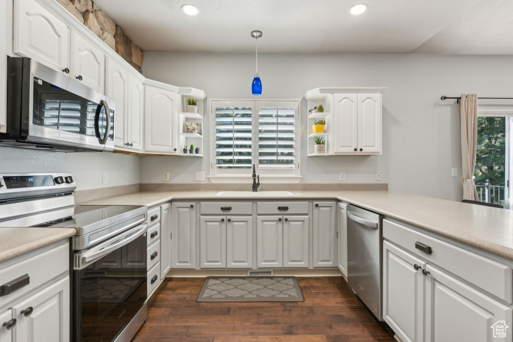 Kitchen with dark wood finished floors, appliances with stainless steel finishes, a sink, and open shelves