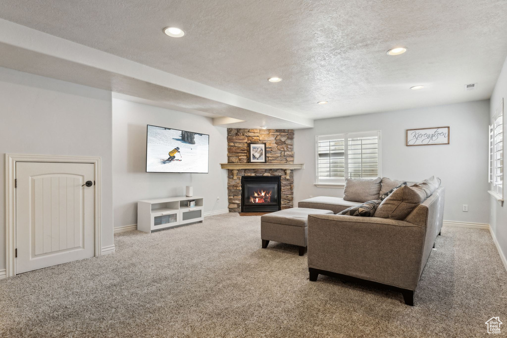Living area featuring carpet floors, baseboards, a fireplace, and a textured ceiling