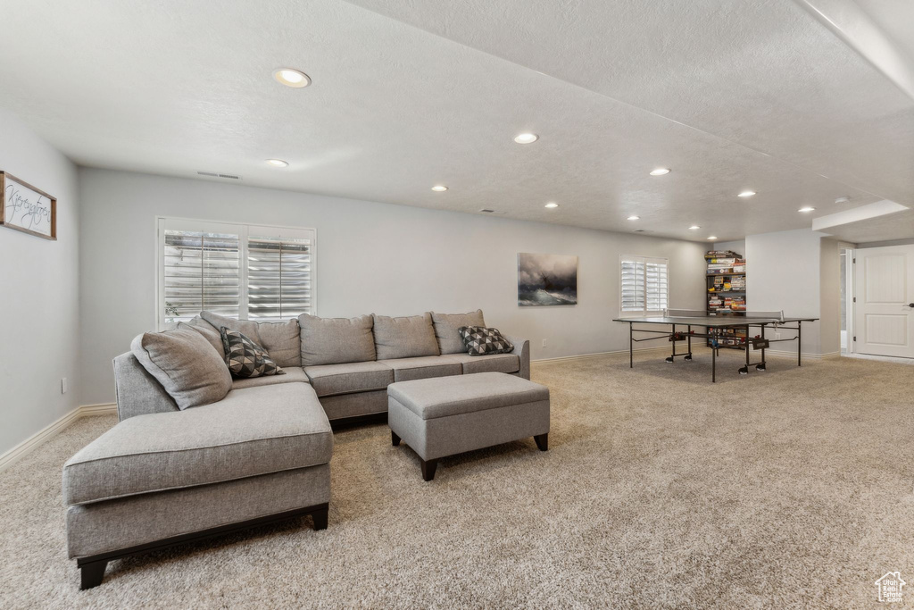 Living area with baseboards, recessed lighting, and light colored carpet