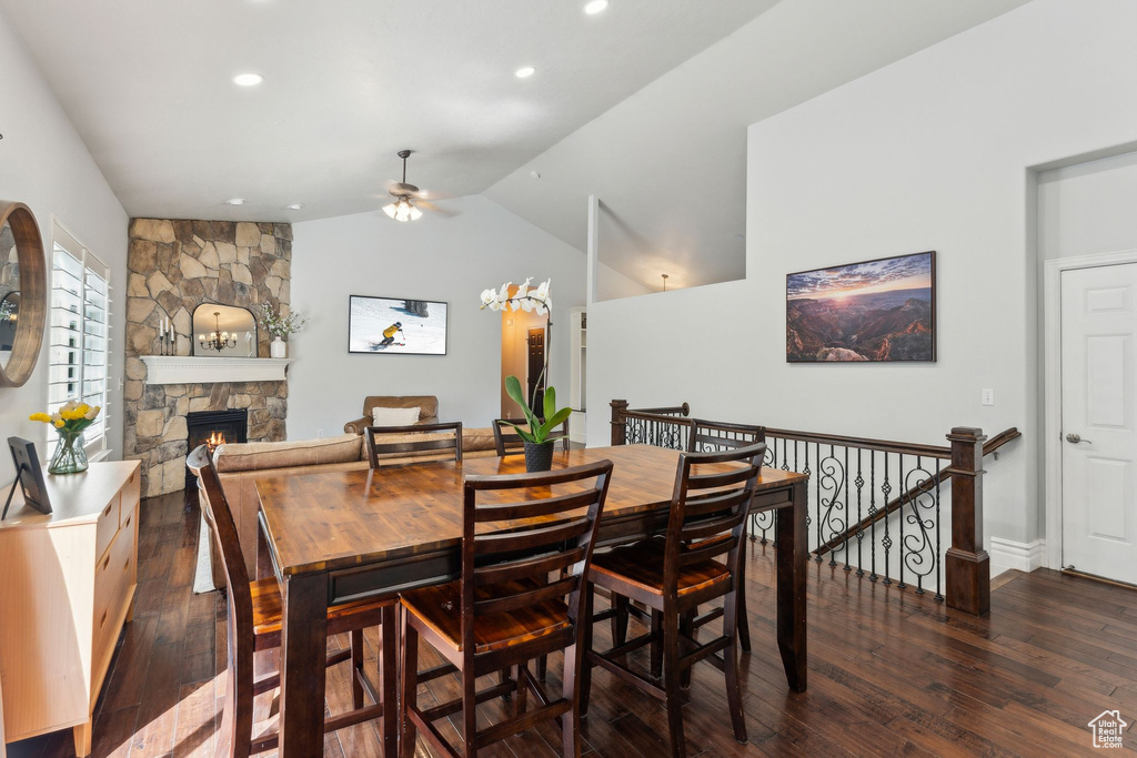 Dining room featuring a stone fireplace, a ceiling fan, recessed lighting, wood finished floors, and lofted ceiling