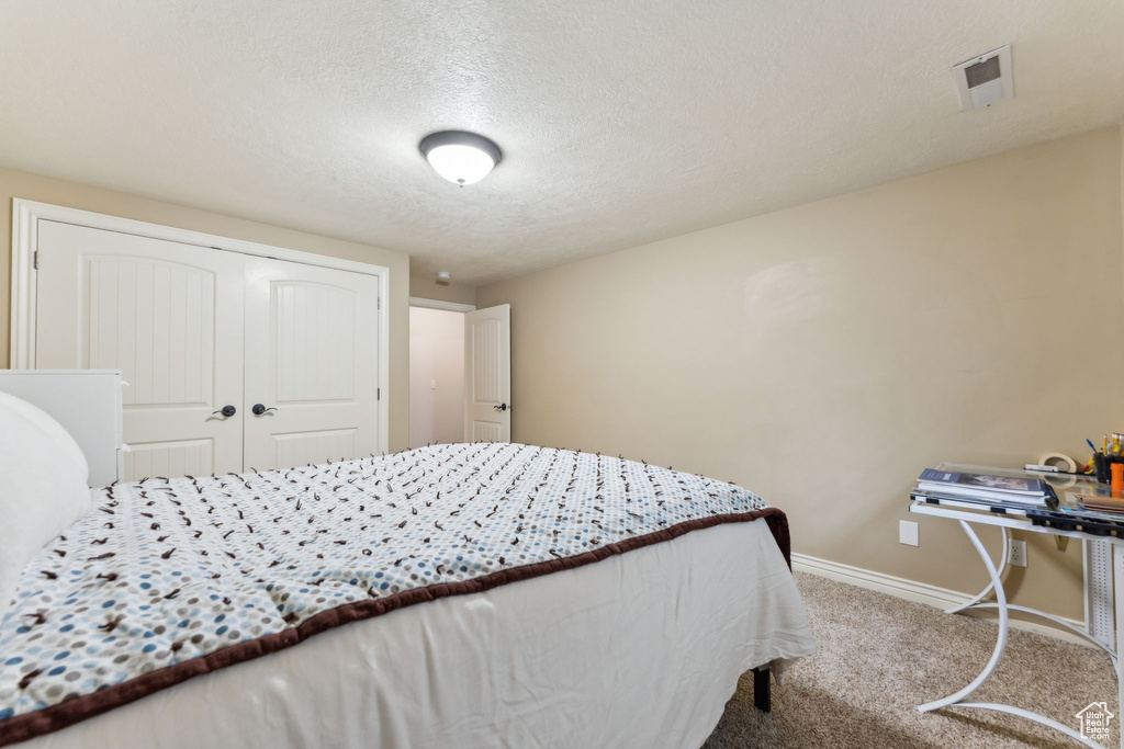 Bedroom featuring carpet, a textured ceiling, a closet, visible vents, and baseboards