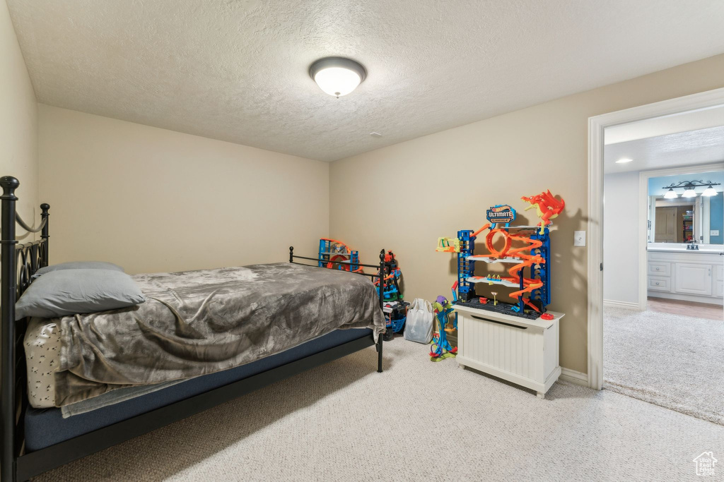 Carpeted bedroom featuring a sink, a textured ceiling, and baseboards