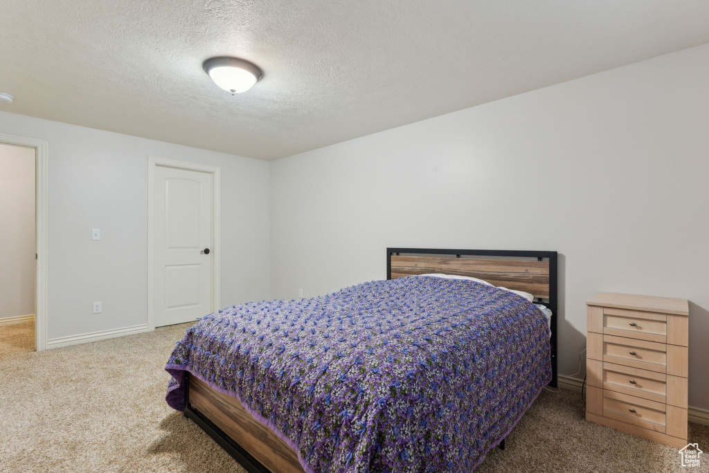 Bedroom featuring baseboards, carpet flooring, and a textured ceiling