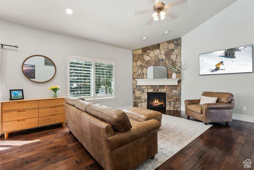 Living room with ceiling fan, a fireplace, dark wood finished floors, lofted ceiling, and baseboards