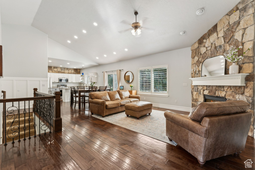 Living room featuring ceiling fan, dark wood finished floors, a fireplace, recessed lighting, and wainscoting