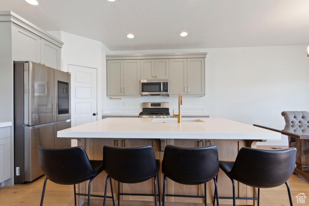 Kitchen featuring light countertops, appliances with stainless steel finishes, gray cabinetry, and light wood-style floors