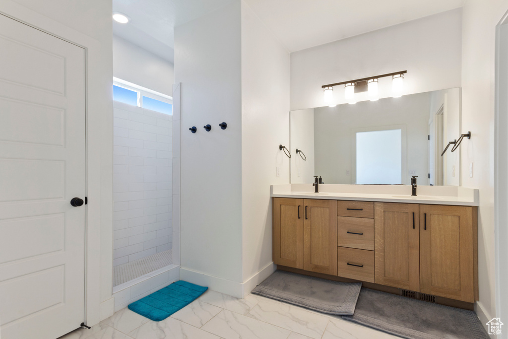 Full bath with a sink, walk in shower, double vanity, and marble finish floor