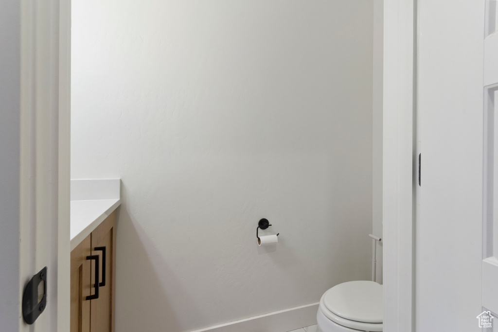 Half bath featuring toilet, vanity, and baseboards