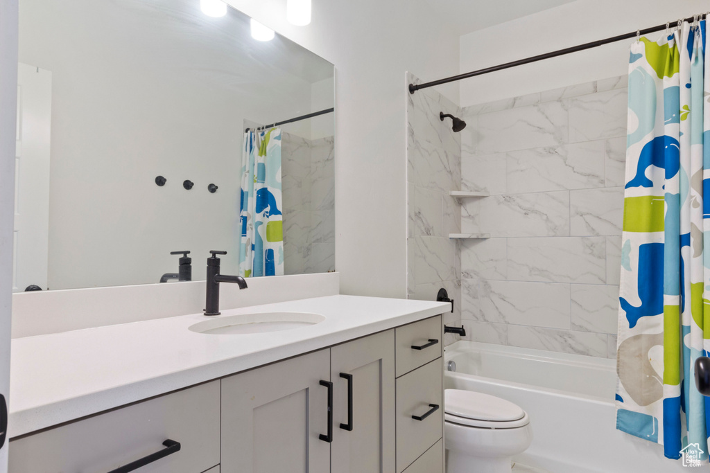 Bathroom with shower / bath combo with shower curtain, vanity, and toilet