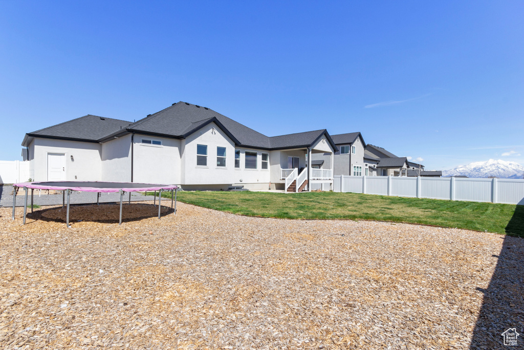 Rear view of property with a yard, fence, a trampoline, and a residential view