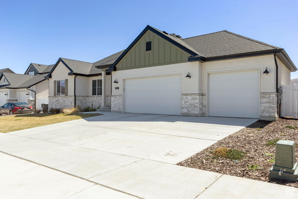 View of front of home featuring a garage, stone siding, and concrete driveway