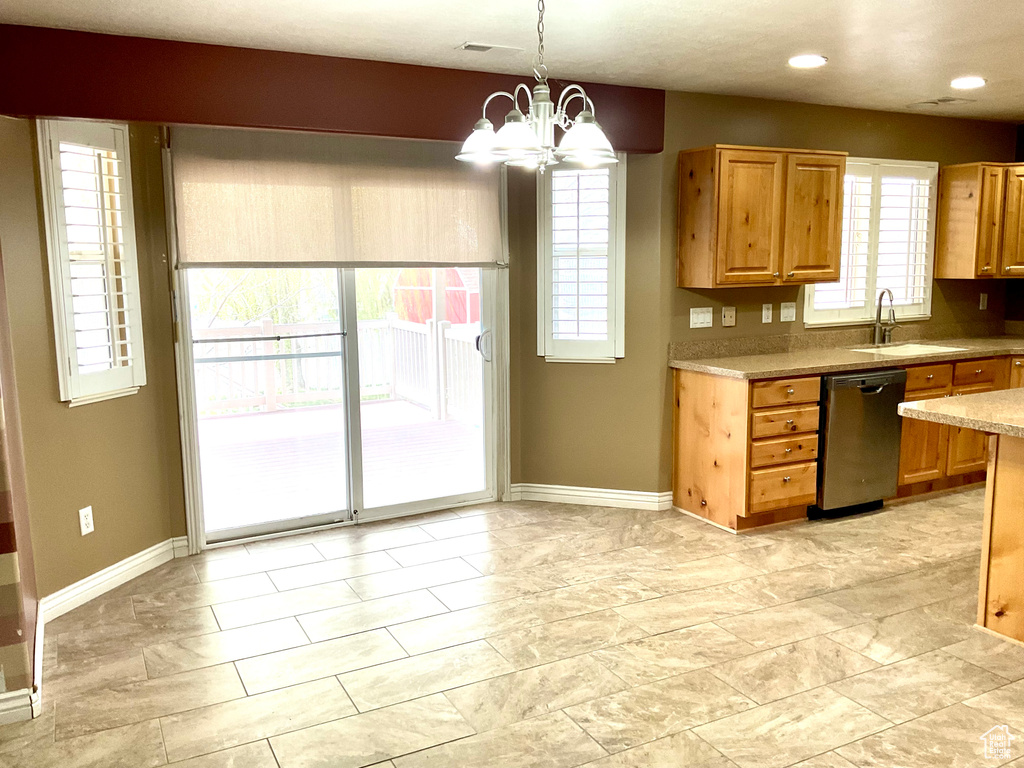 Kitchen featuring a sink, stainless steel dishwasher, baseboards, a chandelier, and light countertops
