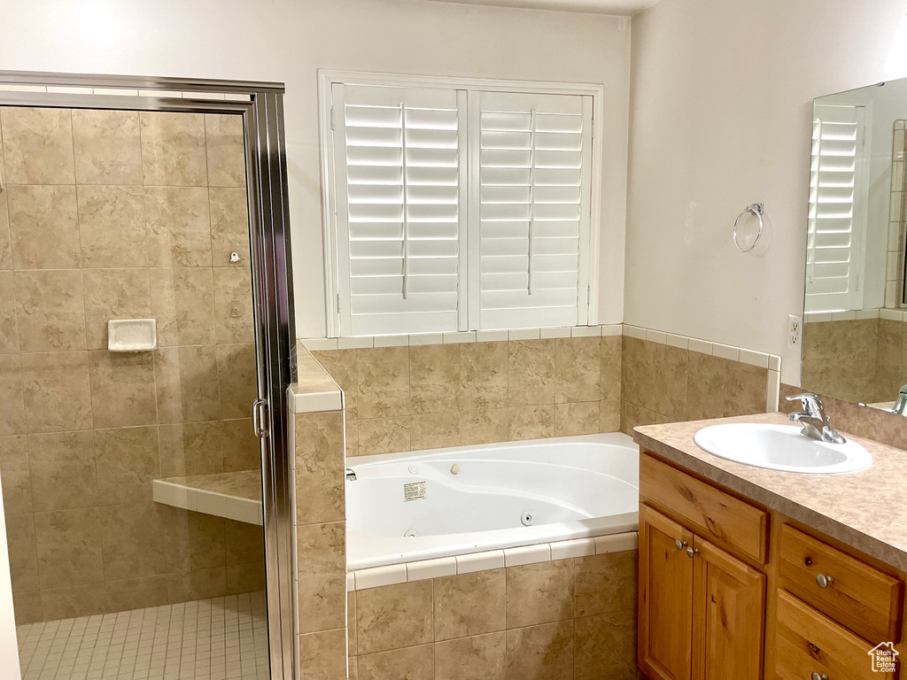 Full bathroom featuring a stall shower, a jetted tub, and vanity
