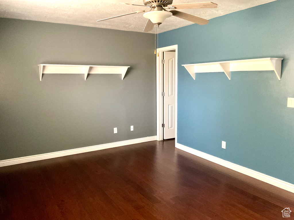 Unfurnished room featuring ceiling fan, dark wood-style floors, and baseboards