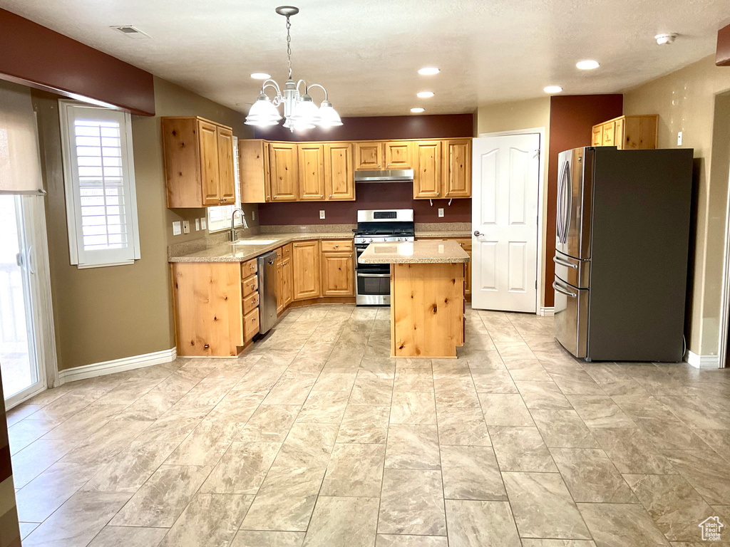 Kitchen with stainless steel appliances, a kitchen island, a chandelier, baseboards, and recessed lighting