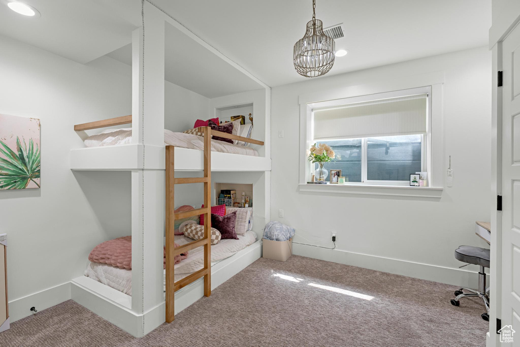 Carpeted bedroom with visible vents, baseboards, and a chandelier