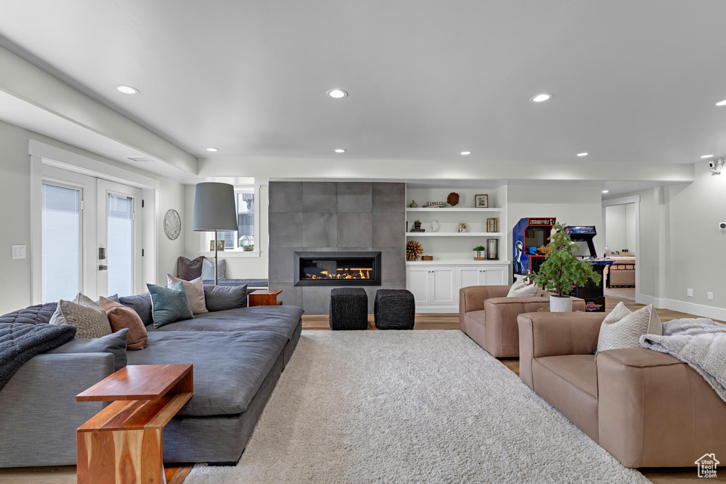 Living room with built in features, a fireplace, recessed lighting, light wood finished floors, and baseboards